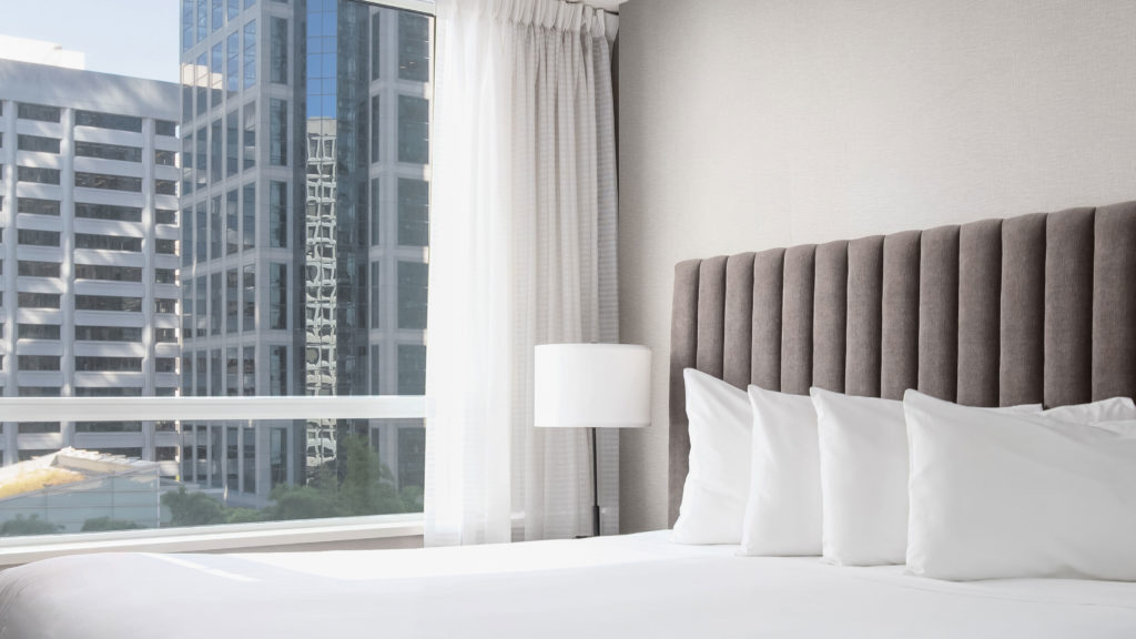 Close up of bed and city views from Carmana hotel suite in Vancouver.