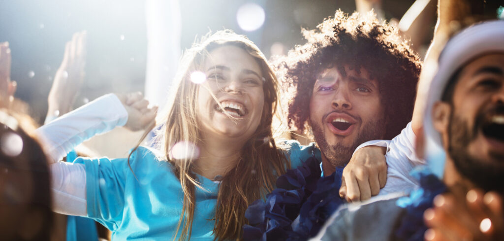Cheerful couple cheering at a live soccer match.